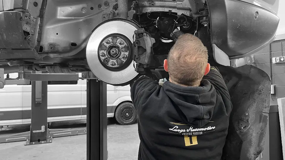 Calum working on a car's front brakes in the Langs Automotive workshop